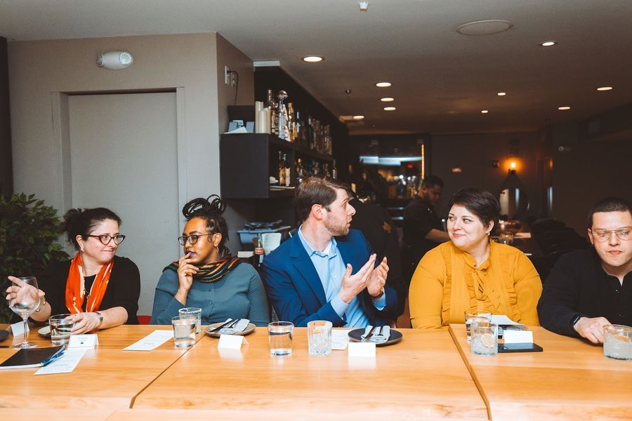 Five guests mid-conversation at the dinner table.